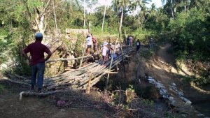 Warga bergotong royong membuat jembatan darurat.